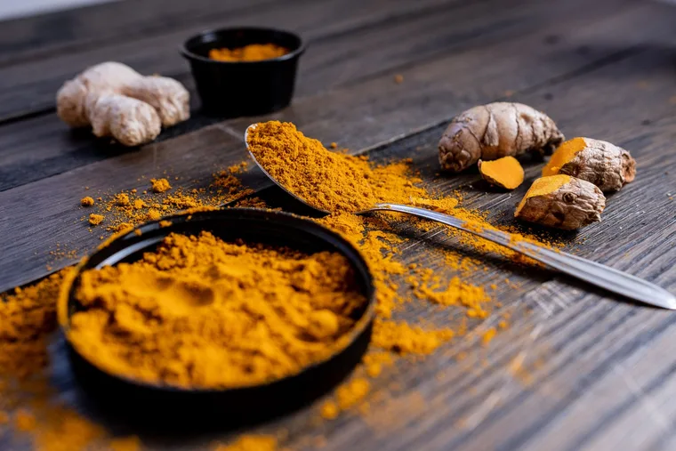 Fresh ginger root and ground ginger powder next to a dog treat bowl, natural remedy for dog motion sickness